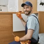 cheerful-male-worker-fixing-cupboard-door-in-kitchen.jpg